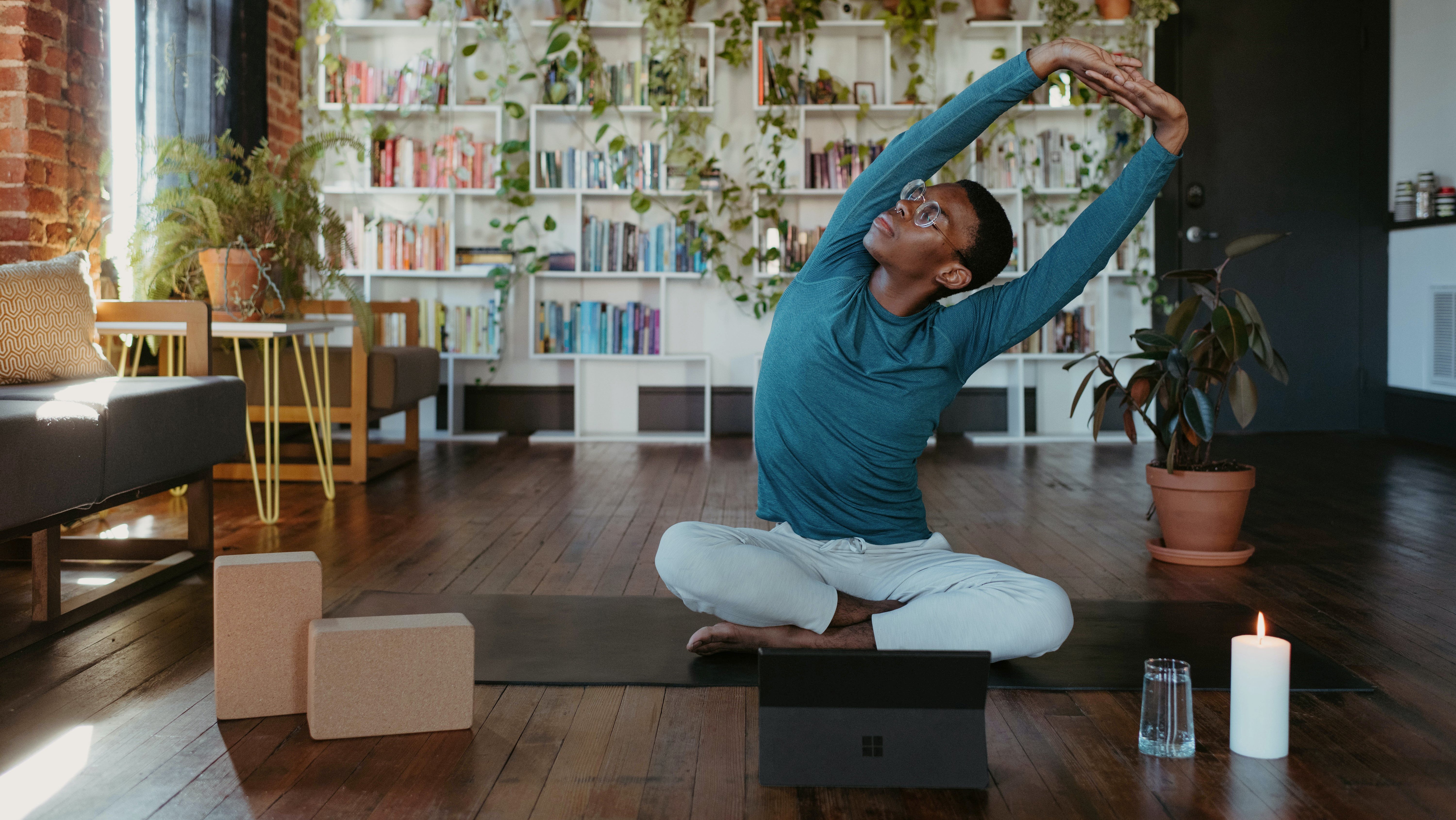 man stretching yoga from home hybrid work wellness laptop