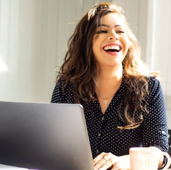 woman laughing while using computer hybrid work square