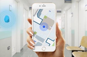 A blue dot on an indoor map mobile app indicates the location of a user inside of a building.